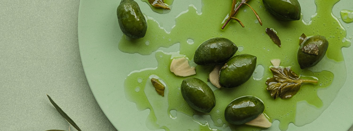 A bowl of green olives beside salted almonds