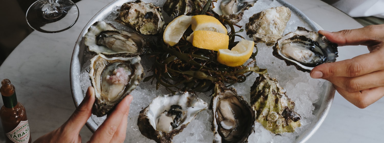 A table of freshly shucked oysters with wine glasses