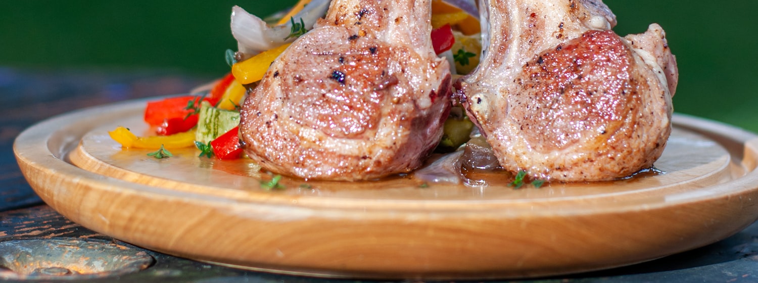 A cooked pork chop on a wooden plate